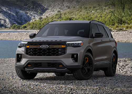Ford Explorer Tremor SUV parked on rocky terrain beside a lake with mountains in the background