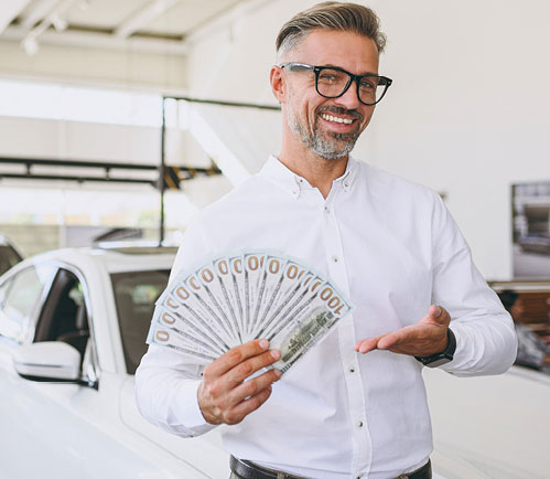 A sales representative holding 100 dollar bills and smiling to the camera
