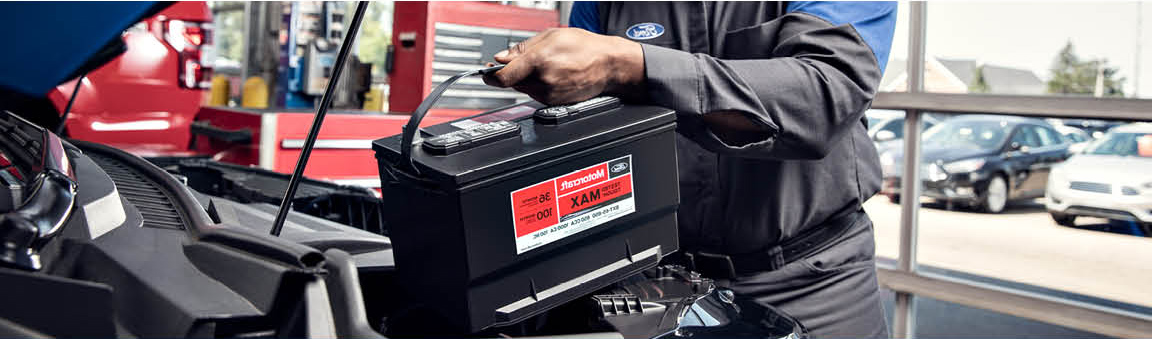 Ford service technician replacing vehicle battery in dealership service center