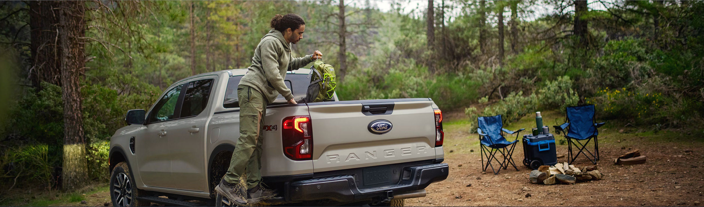 Ford Ranger pickup truck parked at a campsite with outdoor gear and camping chairs