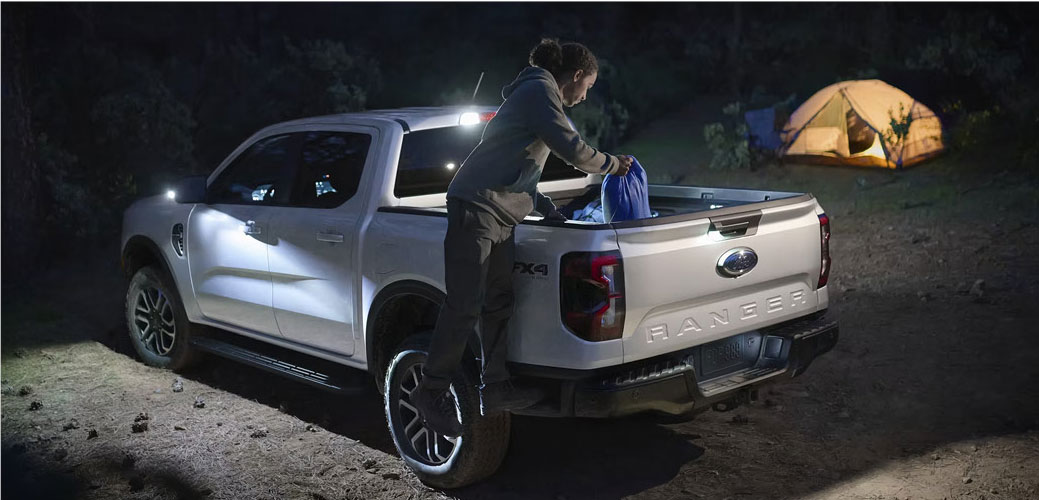 Ford Ranger pickup truck at night with cargo bed lighting at a campsite