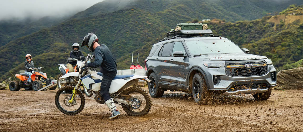 Ford SUV off-roading with dirt bikes on a muddy trail in the mountains