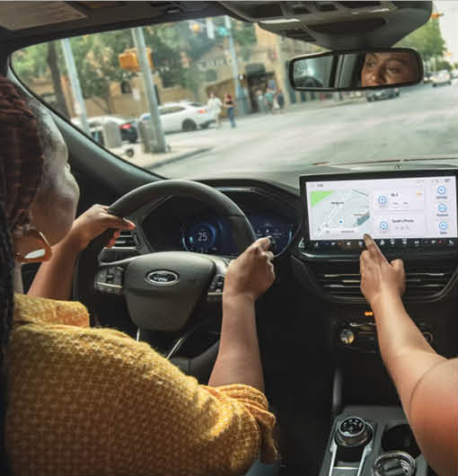 Driver using Ford SUV infotainment navigation system while passenger interacts with touchscreen