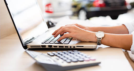 Person calculating car financing costs on laptop with calculator