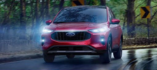 Red Ford SUV driving on a wet road with headlights on