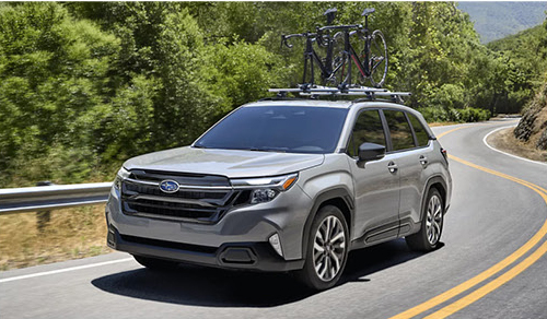 Subaru Forester driving on a scenic road with bicycles mounted on the roof