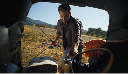 Person loading camping and fishing gear into the back of a Subaru SUV