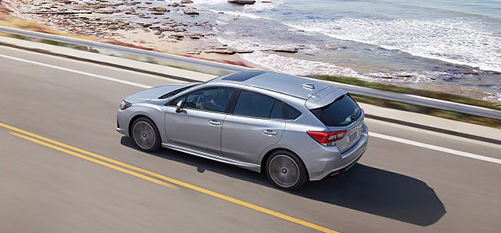Subaru Impreza hatchback driving along a scenic coastal highway