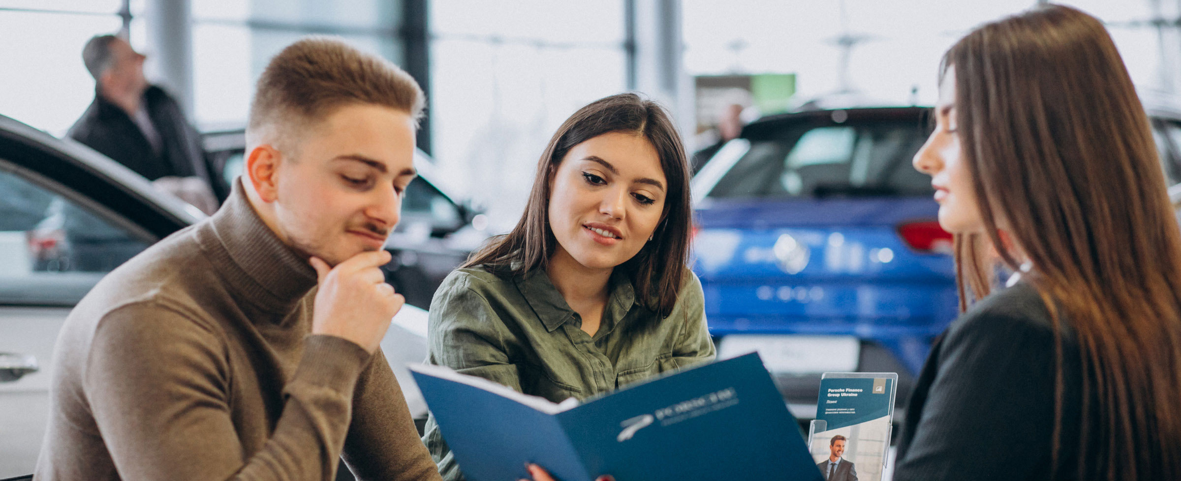 Car buyers reviewing information with dealership representative inside showroom