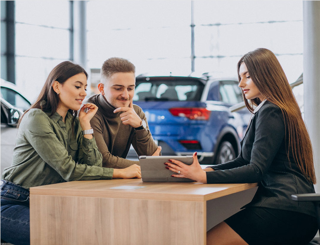 Couple discussing vehicle options with dealership agent using tablet