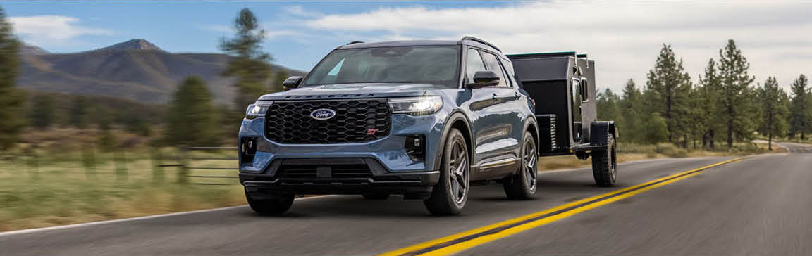 Ford Explorer towing a utility trailer on a scenic highway