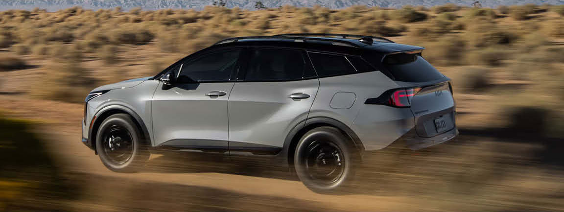 Kia Sportage SUV driving on dirt road in desert landscape
