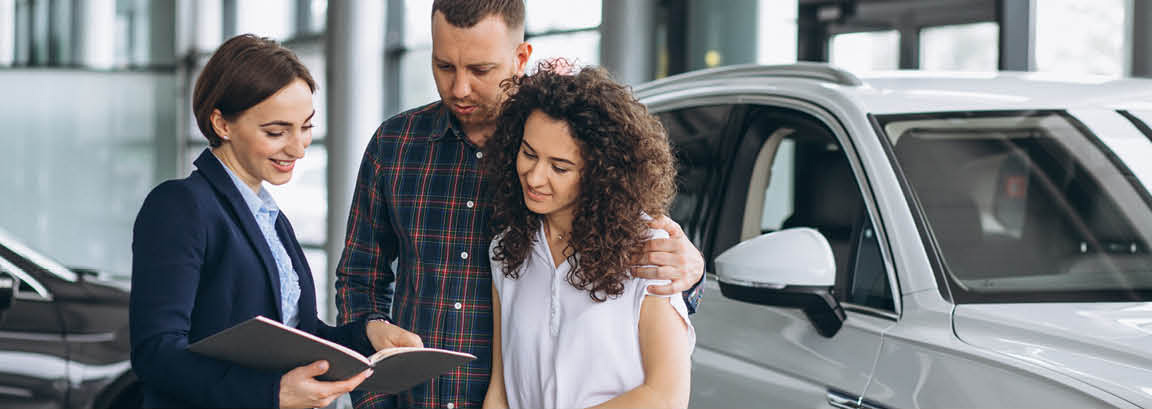 Couple reviewing car purchase details with a dealership salesperson