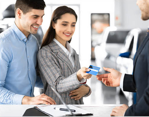 Customer handing credit card to dealership representative during vehicle purchase