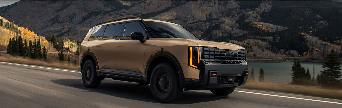 Kia Telluride SUV driving near a lake with scenic mountain background