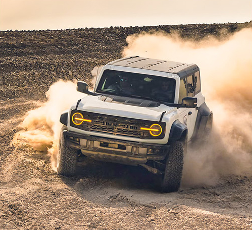 Ford Bronco Raptor driving aggressively through a dusty desert off-road course