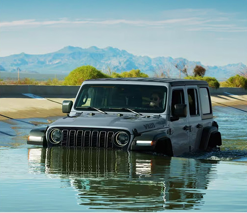 Jeep Wrangler driving through deep water showcasing off-road water-fording performance