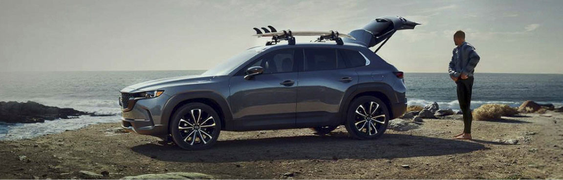 Mazda CX-50 parked along a coastal destination with outdoor gear, emphasizing premium utility, cargo flexibility, and weekend adventure readiness