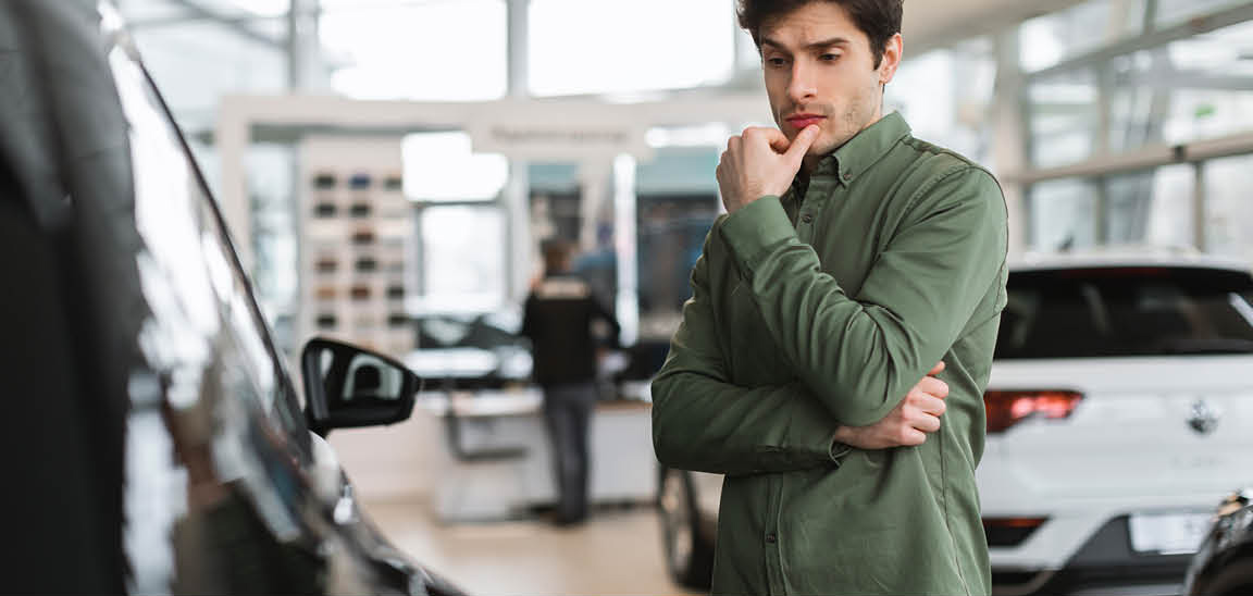 Customer comparing vehicles while shopping at a car dealership showroom