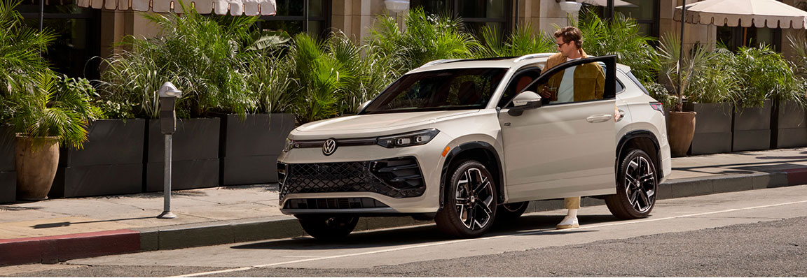 Volkswagen Tiguan parked on city street with driver opening the door