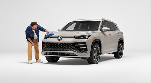 Man cleaning front of Volkswagen Tiguan in studio setting