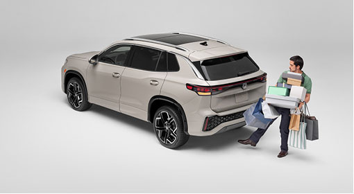 Man carrying shopping bags approaching rear of Volkswagen Tiguan