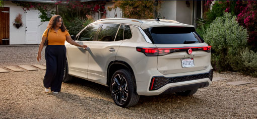 Woman opening driver door of Volkswagen Tiguan parked in driveway
