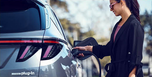 Driver plugging a plug-in hybrid SUV into a charging station