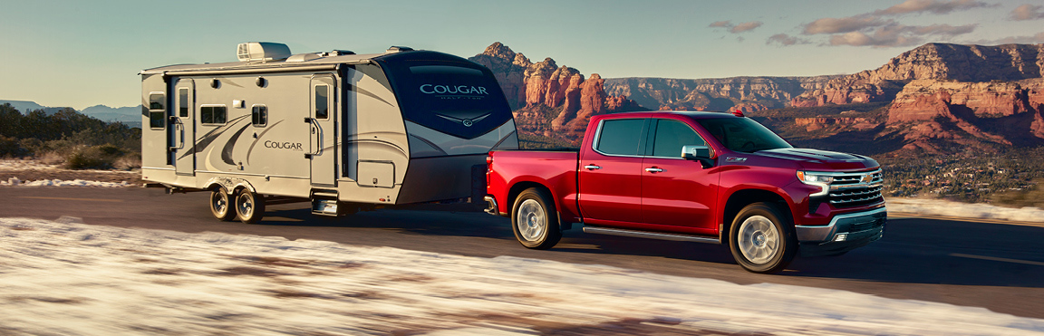 Chevrolet Silverado towing travel trailer on scenic mountain highway