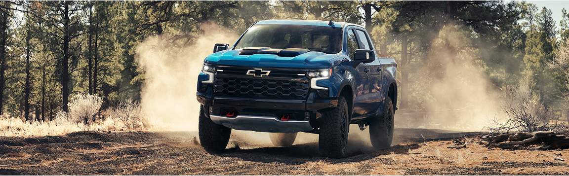 Chevrolet Silverado driving off-road in dusty forest terrain