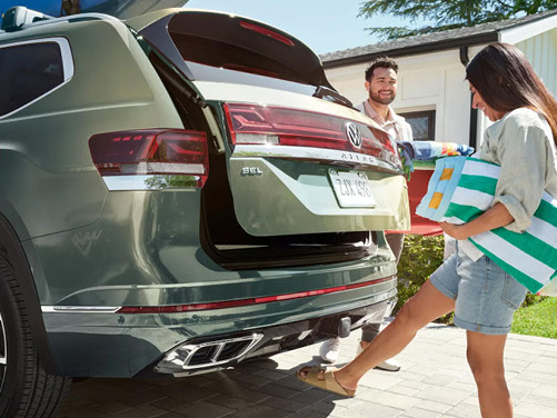 Family loading groceries into the rear cargo area of a Volkswagen Atlas SUV