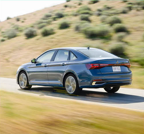 Rear view of Volkswagen Jetta sedan driving through countryside