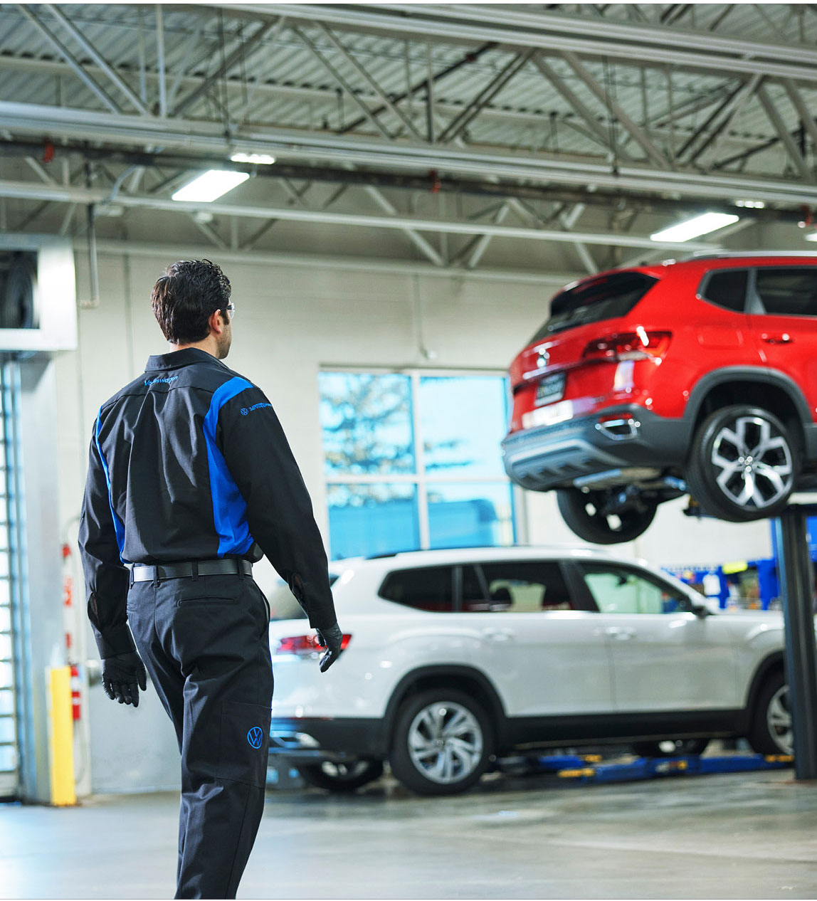 Volkswagen service technician inspecting vehicles inside a dealership service center