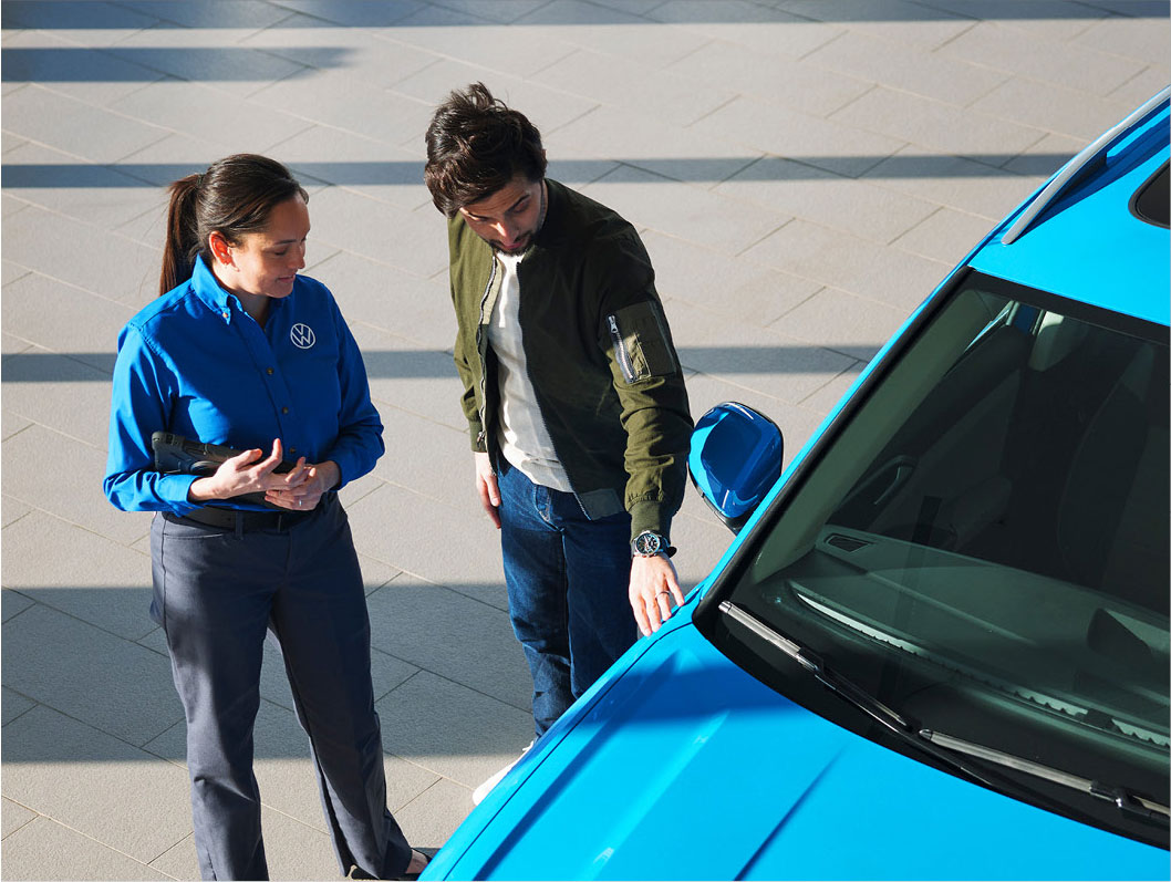 Volkswagen sales associate explaining vehicle features to a customer at the dealership