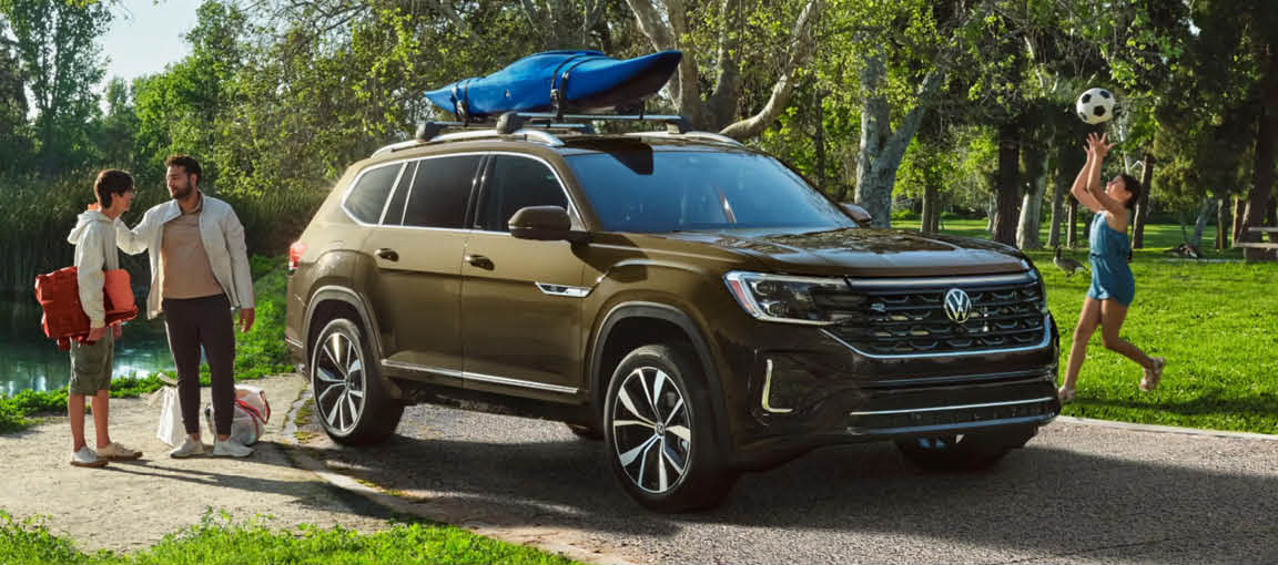 Volkswagen Atlas SUV parked near a park with family loading outdoor gear