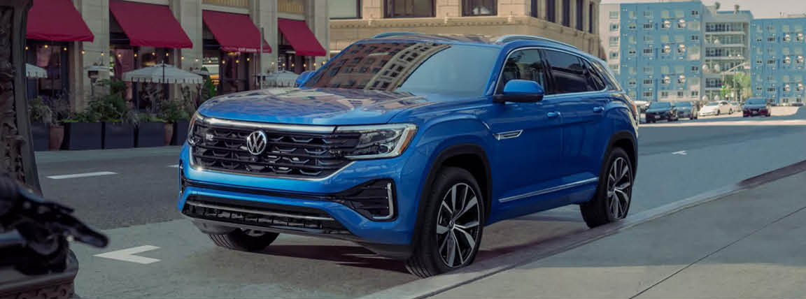 Volkswagen Atlas Cross Sport SUV driving through a downtown city street