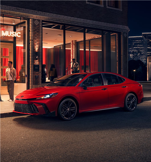red Toyota Camry parked outside modern venue at night