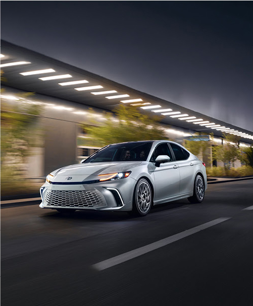 Toyota Camry driving through city at night with illuminated street lights