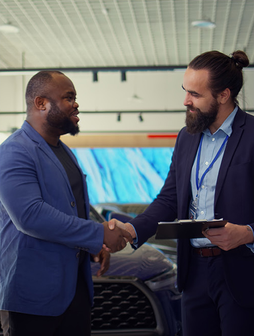 customer shaking hands with car sales representative at dealership