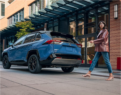 Driver walking away from parked Toyota RAV4 hybrid SUV in city setting