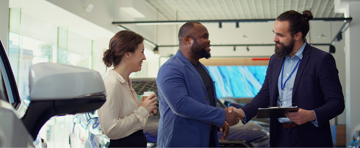 Car buyer shaking hands with dealership salesperson in a showroom