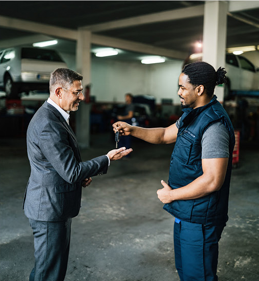 Mechanic handing car keys to a customer inside an automotive service garage