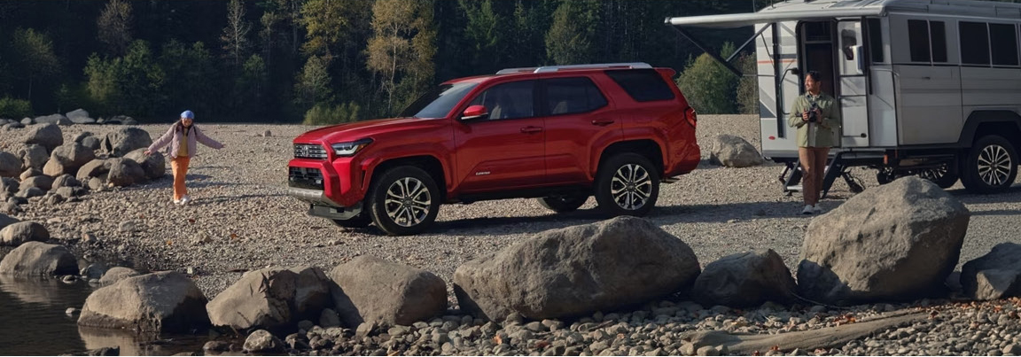 Toyota 4Runner parked at campsite with family near trailer by river
