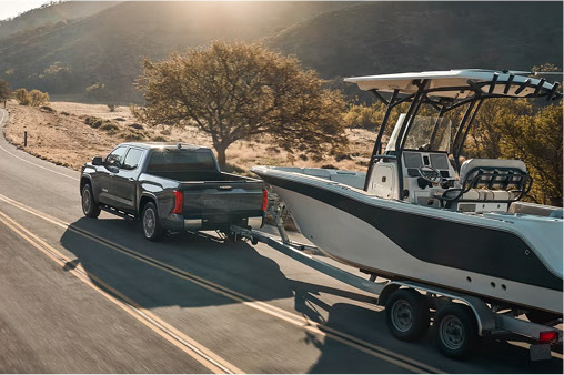 Toyota Tundra towing a large fishing boat along a winding highway