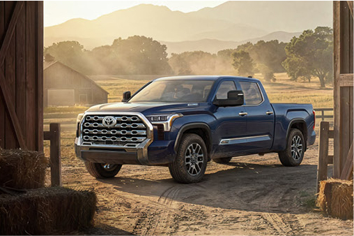 Blue Toyota Tundra parked on a rural property with mountains and farmland in the background