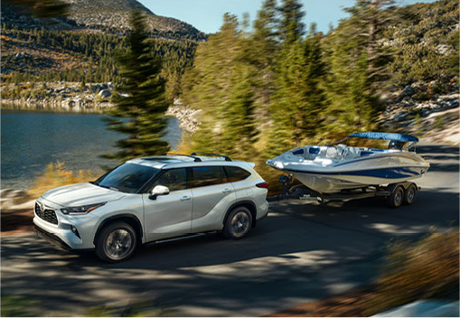 Toyota Highlander towing a speedboat along a scenic lakeside road