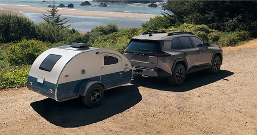 Toyota Grand Highlander towing a compact camping trailer near a coastal destination
