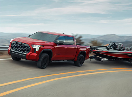 Red Toyota Tundra towing a bass boat on a highway