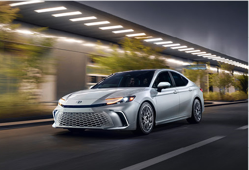 Silver Toyota Camry sedan driving through a city street at night showcasing modern styling and LED lighting