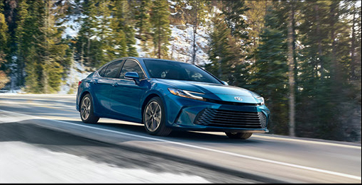 Blue Toyota Camry traveling along a scenic road surrounded by trees and natural scenery